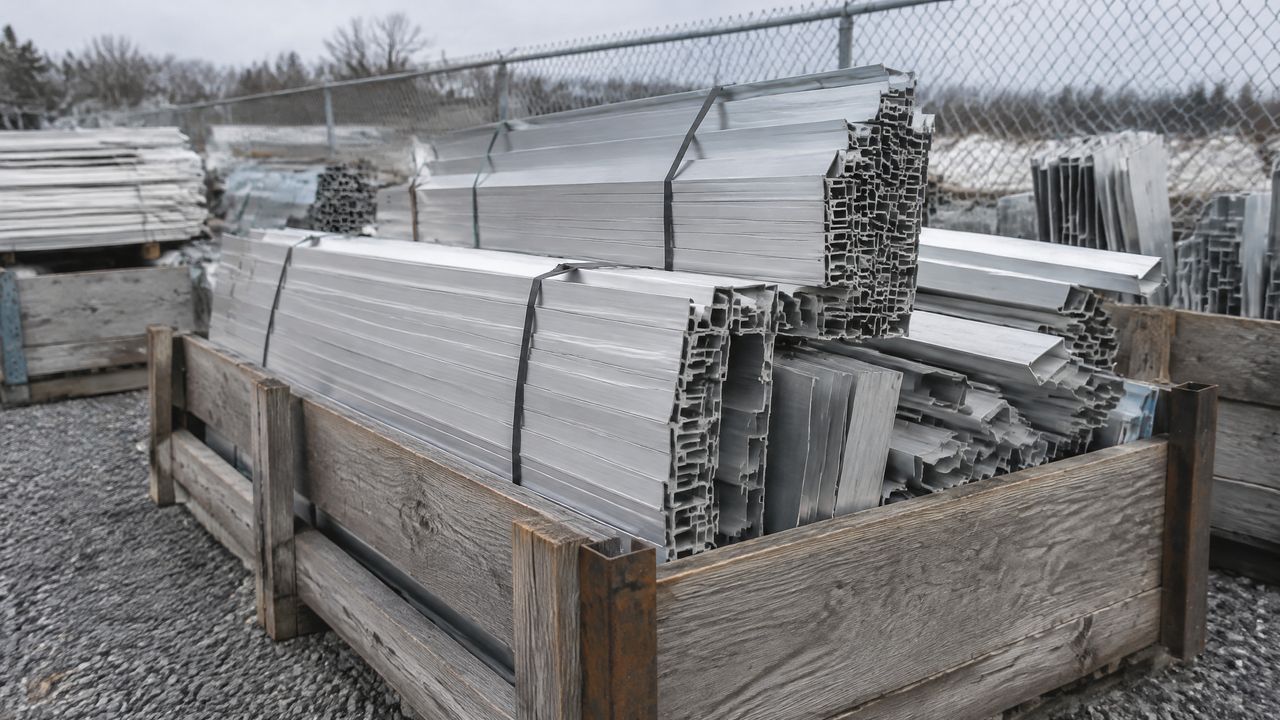 Stacks of aluminum siding and extruded shapes bundled in a bin at a scrap yard